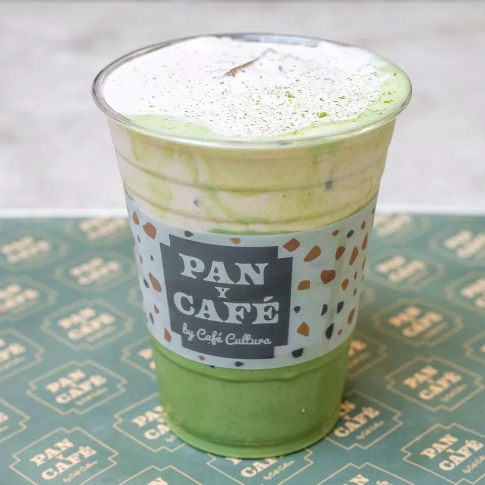 Iced matcha latte with whipped cream and matcha powder, from Pan y Café by Café Cultura.