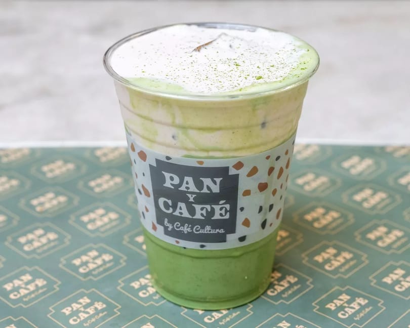 Iced matcha latte with whipped cream and matcha powder, from Pan y Café by Café Cultura.
