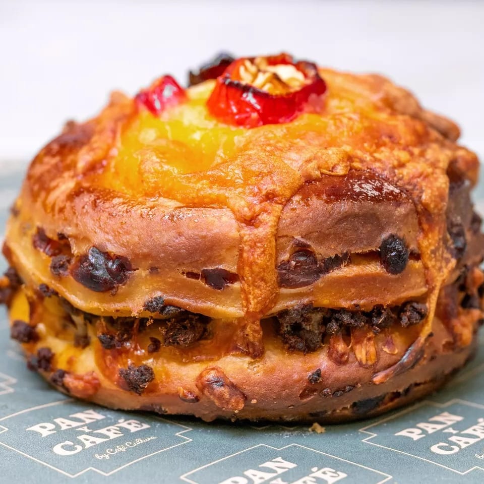 Sweet bread with candied fruit and nuts on a Pan Cafe branded paper.