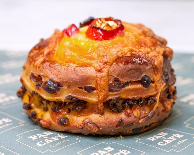Sweet bread with candied fruit and nuts on a Pan Cafe branded paper.